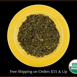 May include: A yellow ceramic plate with a pile of dried green organic mint leaves. The plate has a raised rim and a concentric circle design. The USDA Organic seal is visible in the lower right corner of the image.