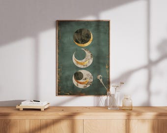 May include: A framed print depicting three moon phases. Each moon phase is a circle with a gold and white crescent against a teal background. The frame is dark wood. The print is displayed on a wooden surface.