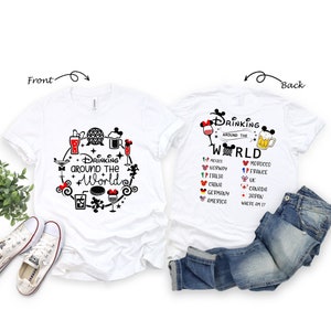 May include: White t-shirt with a black and white graphic design of a Mickey Mouse head with a drink in its hand. The text "Drinking Around the World" is written in a circle around the Mickey Mouse head. The back of the shirt has a list of countries with flags and the text "Drinking Around the World".