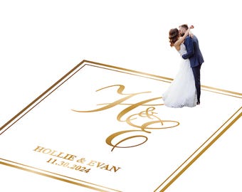 May include: A white wedding invitation with gold lettering and a gold border. The invitation features the initials "H & E" in elegant script, along with the names "Hollie & Evan" and the date "11.30.2024". A couple is kissing in the background.