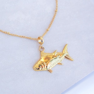 Peut inclure: Un collier en or avec un pendentif en forme de poisson détaillé. La chaîne est composée de petites perles rondes.