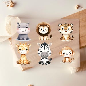 Op de afbeelding: Zes schattige dierillustraties op een transparant vel. De dieren zijn een zebra, een giraffe, een leeuw, een tijger, een nijlpaard en een aap. De illustraties zijn in cartoon-stijl en perfect voor knutselprojecten.