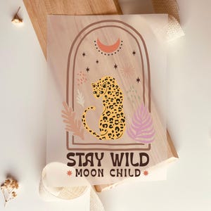Könnte beinhalten: Ein beige-brauner Druck mit einem Leoparden in einem Torbogen mit Sternen und einer Mondsichel. Der Text "Stay Wild *Moon Child*" befindet sich unter dem Torbogen.