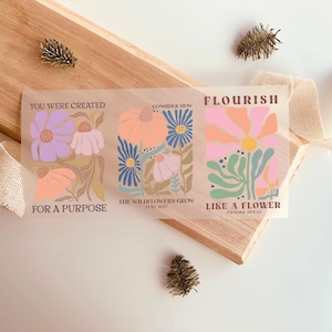 Peut inclure: Trois motifs floraux avec des citations inspirantes. Le premier motif présente des fleurs violettes et roses avec le texte "Vous avez été créé pour un but". Le deuxième motif présente des fleurs roses, bleues et orange avec le texte "Considérez comment les fleurs sauvages poussent (Luc 12:27)". Le troisième motif présente des fleurs roses, vertes et jaunes avec le texte "Épanouissez-vous comme une fleur (Psaumes 103:15)".