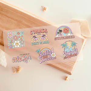 Può includere: Sei adesivi colorati con disegni a tema estivo. Gli adesivi presentano frasi come "L'estate è uno stato d'animo", "Salato ma dolce" e "Goditi le onde".