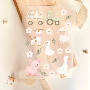 Peut inclure: Feuille d'autocollants d'animaux de la ferme avec un tracteur, une vache, un mouton, un cochon et des canards. Les autocollants sont dans un style aquarelle avec une palette de couleurs pastel, avec des accents blancs, roses et verts. Les autocollants sont disposés avec des éléments floraux et de feuilles.