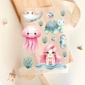 Può includere: Un foglio di adesivi con creature acquatiche. Include una pastinaca sorridente, una medusa, una tartaruga, un cavalluccio marino e una sirena. Gli adesivi sono in colori pastello, con effetto acquerello, e sono adatti per lavori creativi per bambini.