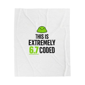 May include: White blanket with the text "THIS IS EXTREMELY 6.7 CODED" in black and green. A green cartoon blob is at the top. The blanket is folded and has a wrinkled texture.