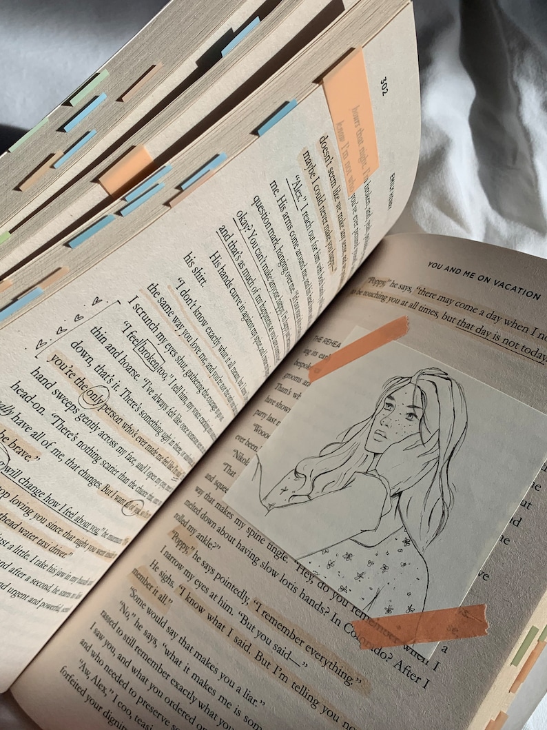Pode incluir: Um close-up de um livro com uma ilustra&ccedil;&atilde;o desenhada &agrave; m&atilde;o de uma mulher com cabelo comprido. O livro est&aacute; aberto em uma p&aacute;gina com texto sobre f&eacute;rias. O texto inclui a frase "You and Me on Vacation".