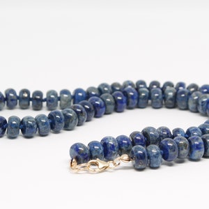 May include: A blue lapis lazuli beaded necklace with a gold clasp.
