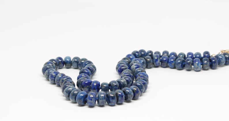 May include: A strand of dark blue lapis lazuli beads, strung on a gold thread.