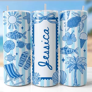May include: A blue and white striped tumbler with beach-themed illustrations. The design includes a sun, starfish, fish, sunglasses, flip-flops, a beach chair, a turtle, an ice cream cone, a palm tree, and the name "Jessica".