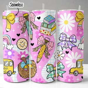 May include: A pink tumbler with a seamless pattern of school-themed illustrations. The design includes pencils, bows, books, daisies, rainbows, smiley faces, hearts, and school buses. The tumbler has a straw and the word "Seamless" is in the top left corner.