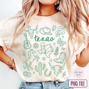May include: Cream-colored t-shirt with a green Texas-themed graphic. The design includes a guitar, longhorn skull, cowboy hat, snake, butterfly, horse, cactus, Texas flag, and the word "Texas".