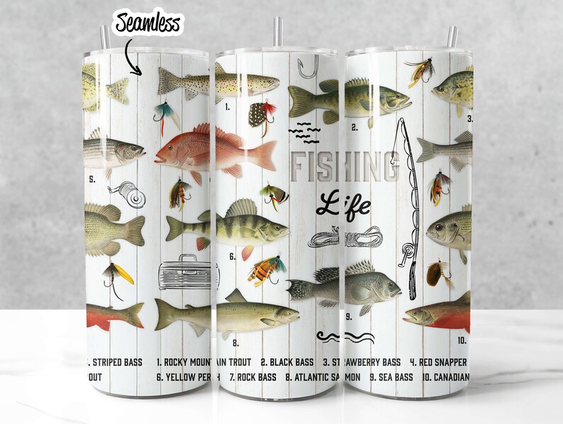 May include: A white tumbler with a woodgrain background and illustrations of different types of fish. The text "FISHING Life" is printed on the tumbler. The tumbler is labeled with the names of the fish, including Striped Bass, Rocky Mountain Trout, Black Bass, Strawberry Bass, Red Snapper, Yellow Perch, Rock Bass, Atlantic Salmon, Sea Bass, and Canadian.