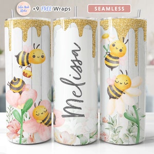 May include: A white tumbler with a gold glitter design and a dripping gold paint effect. The tumbler features a floral design with bees and the name "Melissa" written in black. The tumbler is seamless.