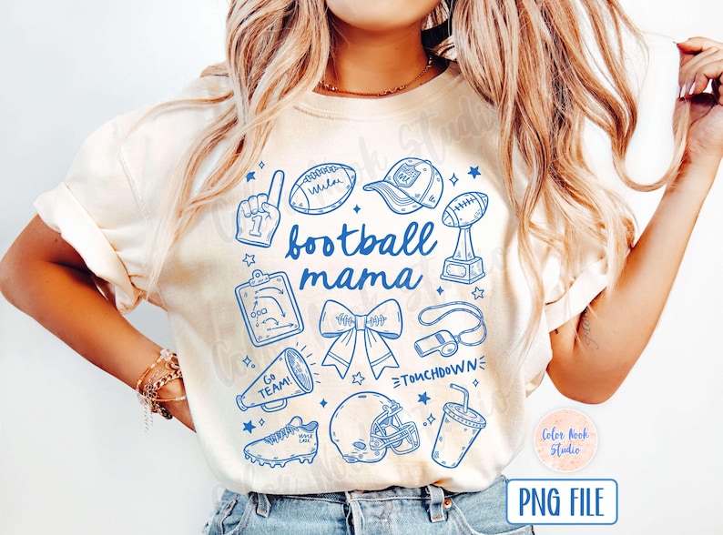 May include: A white t-shirt with a blue graphic design that says "football mama". The graphic includes a football, a whistle, a cheerleader's bow, a football helmet, a trophy, a megaphone, a football play diagram, and a football player's hand making a number one sign.