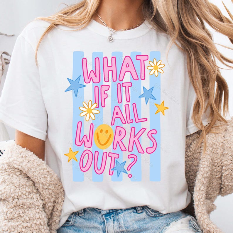 May include: White t-shirt with the text "WHAT IF IT ALL WORKS OUT?" in pink, with blue stars, yellow stars, and daisy accents. The shirt has blue vertical stripes in the background.