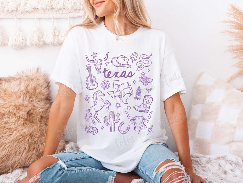 May include: White t-shirt with a purple Texas-themed graphic. The design includes a guitar, cowboy hat, longhorn skull, horse, cactus, and the word "Texas". The shirt is a relaxed fit.