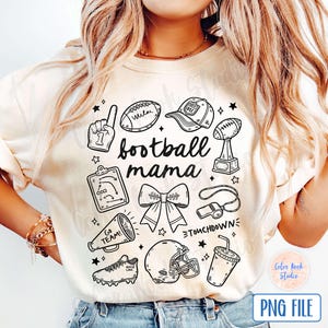 May include: A white t-shirt with a black and white graphic design featuring the text "football mama" and various football-related icons, including a football, a whistle, a cheerleader's bow, and a football helmet.