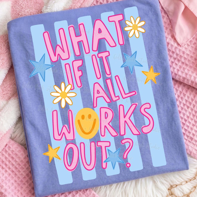 May include: A light purple t-shirt with the phrase "WHAT IF IT ALL WORKS OUT?" in pink lettering. The design includes blue stripes, yellow stars, white daisies, and a yellow smiley face.