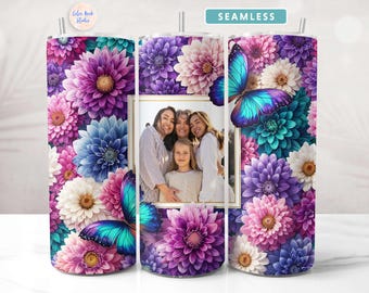May include: A stainless steel tumbler with a floral design featuring butterflies and a photo of four people. The tumbler has a white background with purple, pink, blue, and green flowers. The photo is in a rectangular frame and shows a group of people smiling. The text "SEAMLESS" is printed on the tumbler.