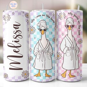 May include: Three stainless steel tumblers with a white background and a checkered pattern in pink and blue. Each tumbler features a cartoon goose wearing a white bathrobe and sunglasses with the text "silly goose on the loose".