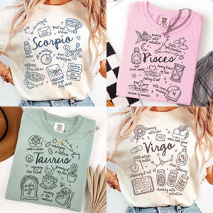 May include: Four t-shirts with zodiac-themed designs. The shirts are cream, pink, sage green, and off-white. Each shirt features a different zodiac sign: Scorpio, Pisces, Taurus, and Virgo, along with related illustrations and text.