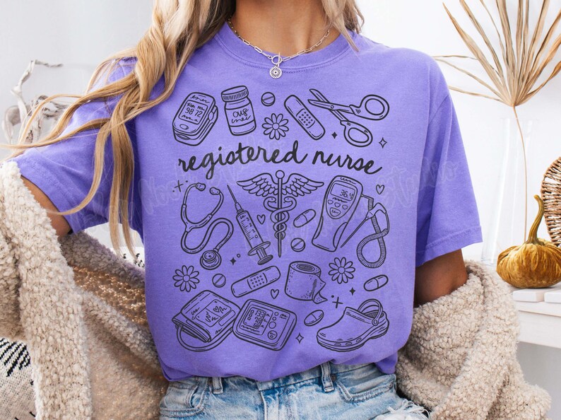 Op de afbeelding: Paars T-shirt met een grafisch ontwerp van medische instrumenten en de tekst "registered nurse".