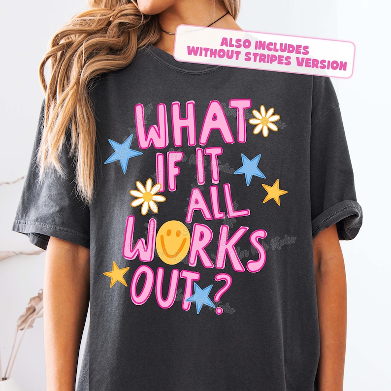 May include: Dark gray t-shirt with the phrase "WHAT IF IT ALL WORKS OUT?" in pink, outlined in white. The design includes blue stars, yellow stars, and daisy flowers. The shirt also includes a smiley face.