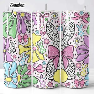 Puede incluir: Tres vasos de acero inoxidable con un patr&oacute;n floral rosa, blanco y verde. El patr&oacute;n incluye conejos, lazos y flores. Los vasos son sin costuras.