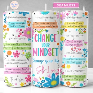 May include: Three white tumblers with colourful floral designs and motivational quotes. The quotes are "Change Your Mindset", "I'm Not Enough", and "I'm Too Busy".
