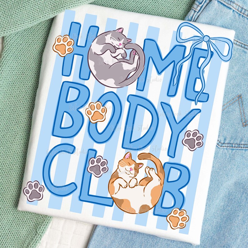 May include: White t-shirt with blue stripes and the words "HOME BODY CLUB" in blue. The shirt features illustrations of two cats and paw prints. One cat is gray and white, curled up, and the other is orange and white, lying on its back.