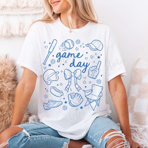 K&ouml;nnte beinhalten: Wei&szlig;es T-Shirt mit einem blauen Grafikdesign von Baseball-Motiven und dem Text "game day".