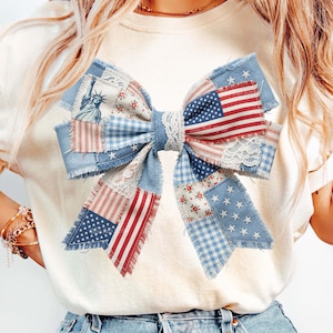 May include: A patriotic bow with a patchwork design incorporating the American flag, Statue of Liberty, and floral patterns. The bow uses red, white, and blue fabrics, including denim, gingham, and lace, for a rustic, handcrafted look. Ideal for Independence Day.
