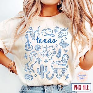 May include: Cream-colored t-shirt featuring blue illustrations of Texas symbols, including a guitar, longhorn skull, cowboy hat, and the word "Texas". The design also includes a horse, cactus, and Texas flag.