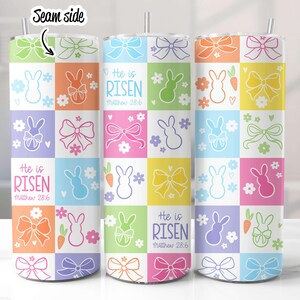 May include: Three stainless steel tumblers with a colorful Easter design. The design features pastel pink, yellow, blue, green, and orange squares with bunnies, bows, and carrots. The text "He is Risen" and "Matthew 28:6" is printed on the tumblers.