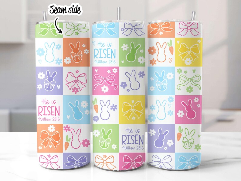 May include: Three stainless steel tumblers with a colorful Easter design. The design features pastel pink, yellow, blue, green, and orange squares with bunnies, bows, and carrots. The text "He is Risen" and "Matthew 28:6" is printed on the tumblers.
