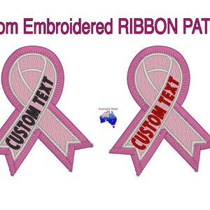 May include: Two pink ribbon patches with white outlines. The ribbon is embroidered with the text "CUSTOM TEXT" in black and red.