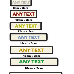 May include: Set of seven custom embroidered patches in various colours. Each patch is rectangular and features the text "ANY TEXT" in a different colour. The patches are arranged in a vertical stack, with the smallest patch at the top and the largest patch at the bottom. The patches are all 3 cm wide and range in length from 8 cm to 20 cm.