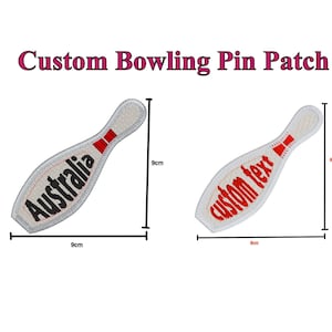 Pode incluir: Patch branco em forma de pino de boliche com bordado vermelho e preto. O patch mede 9 cm de largura e 9 cm de altura. O texto "Austrália" é bordado em preto no patch.