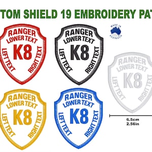 Op de afbeelding: Vijf geborduurde patches in verschillende kleuren, elk met een schildvorm met de tekst "RANGER LOWER TEXT K8" rond de rand. De patches zijn 8,5 cm hoog en 6,5 cm breed.