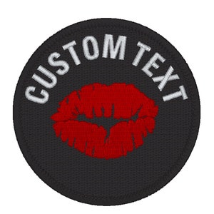 Könnte beinhalten: Ein runder, schwarzer, gestickter Aufnäher mit dem weißen Text "CUSTOM TEXT", der sich oben wölbt. In der Mitte befindet sich ein rotes, gesticktes Bild von Lippen.