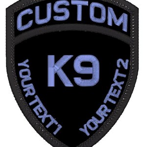 May include: Black and blue embroidered patch in the shape of a shield. The patch says "CUSTOM" at the top and "YOUR TEXT 1" and "YOUR TEXT 2" on the sides. In the centre is the text "K9" in blue.