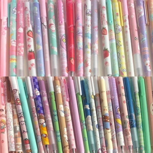 May include: A collection of colorful pens with various cute designs, including strawberries, flowers, and cartoon characters. The pens are arranged in a row, showcasing their different patterns and colors.