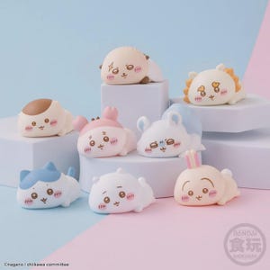 May include: A collection of eight small, smooth, cartoon-style animal figurines in various pastel colors including white, pink, blue, and tan. Each figurine features a rounded, reclining body, a simple face with blushing cheeks, and a small tail.
