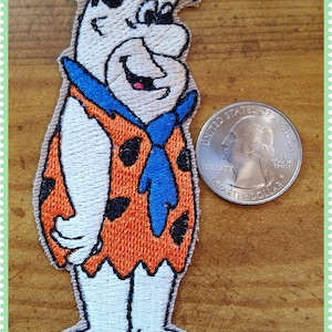 May include: Embroidered patch of Fred Flintstone from the cartoon series The Flintstones. The patch is orange, blue, white, and black. The patch is about the size of a US quarter.