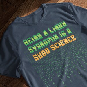 May include: A dark blue t-shirt with the text "BEING A LINUX SYSADMIN IS A SUDO SCIENCE" in green and yellow letters. The background of the shirt is a pattern of green and yellow binary code.