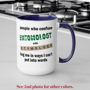May include: White ceramic mug with a blue rim and handle. The mug features a humorous saying about entomology, the study of insects, and etymology, the study of word origins. The text reads: "People who confuse entomology with etymology bug me in ways I can't put into words."