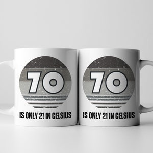 A white 11-ounce ceramic mug with a comfortable C-handle and rounded edges. The black and white design displays the words 70 Is Only 21 in Celsius.